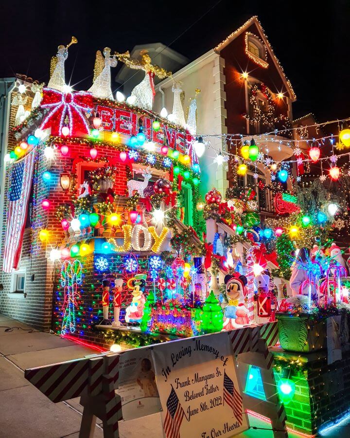 Dyker Heights Christmas Lights New York City USA Non-Touristy Activities for Return Visitors to New York City A house in Dyker Heights, New York City, USA. The house is absolutely covered in Christmas decorations and lights, with some saying Joy and Believe and lots of figures like angels and snowmen everywhere. Out the front of the house is a barrier with a sign on it dedicating the decorations to someone "Non-Touristy Activities for Return Visitors to New York City"