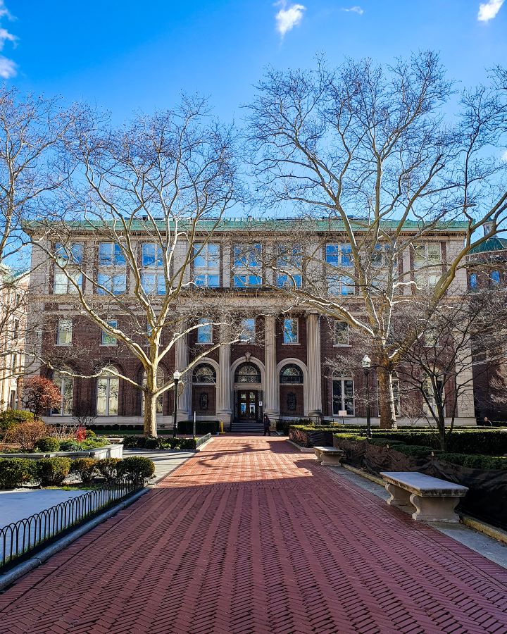 Columbia University New York City USA Non-Touristy Activities for Return Visitors to New York City A red brick path leading up to a big maroon and white building on the Columbia University campus in New York City, USA. There are trees around the building and bushes along the path leading up to it "Non-Touristy Activities for Return Visitors to New York City"