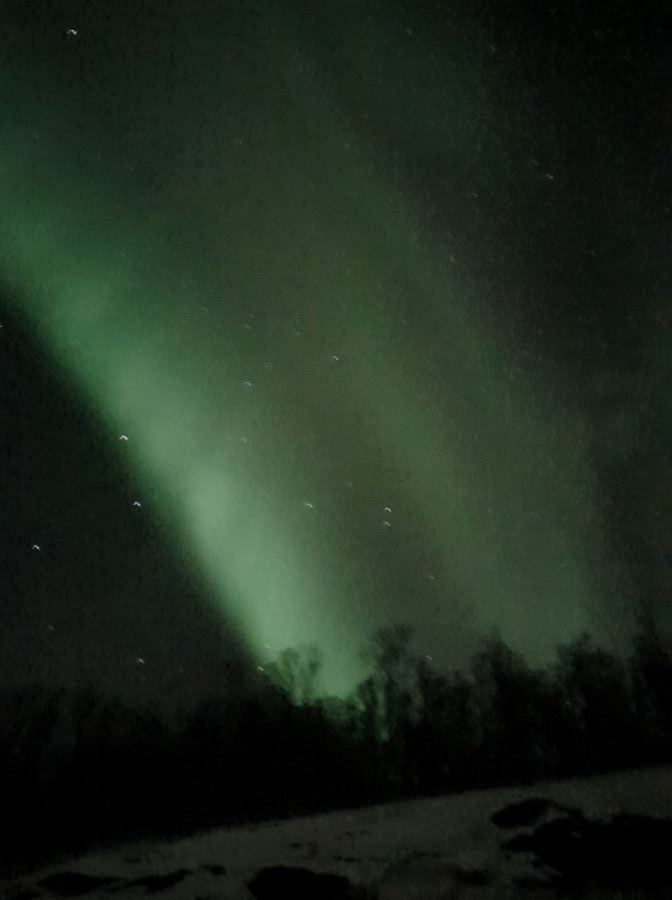 Best Things To Do in the City of Tromsø, Norway A big green light streak going through the dark sky outside Tromsø. Norway. "Best Things To Do in the City of Tromsø, Norway"