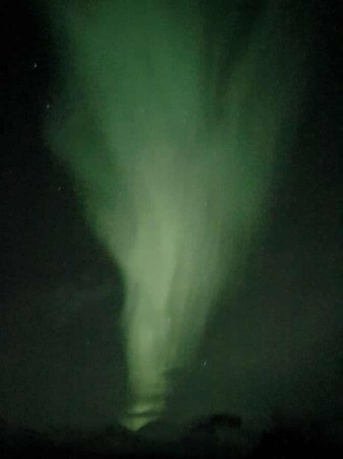 Best Things To Do in the City of Tromsø, Norway A big green light streak going through the dark sky outside Tromsø. Norway. "Best Things To Do in the City of Tromsø, Norway"