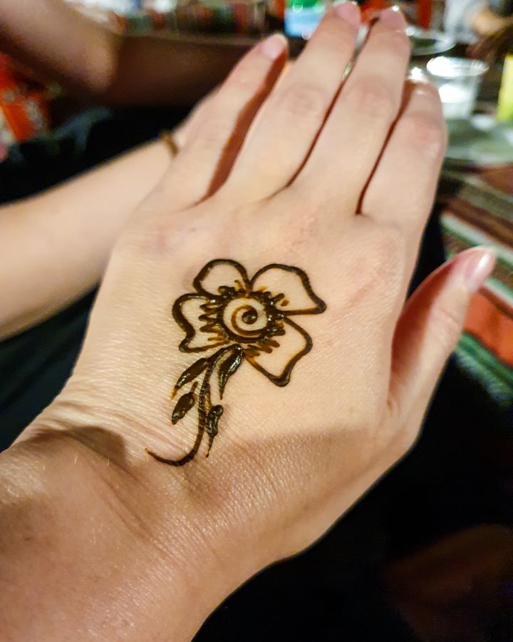 A hand with a flower drawn in brown henna on it in the Arabian desert, UAE. "Dubai Desert Safari Experience: Detailed Get Your Guide Review"