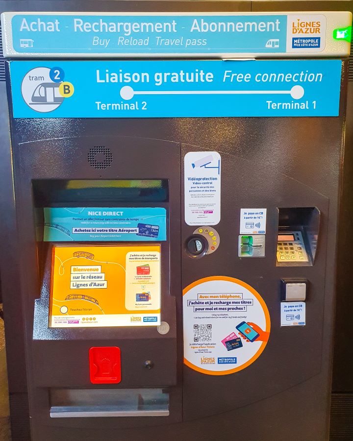 A ticket machine in Nice, France. The machine is grey with different signs on it in both French and English. There's also a screen, a place to pickup tickets and a little card machine on it. How to Navigate Public Transport in and Around Nice, France