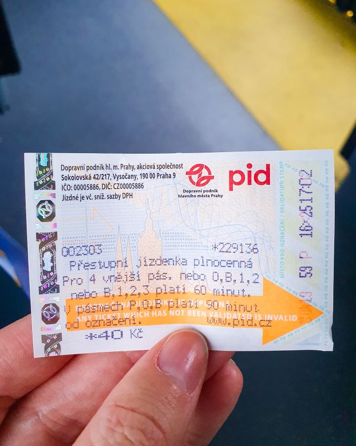 Prague Czechia A Complete Guide to Prague Public Transport A hand holding a little ticket with an orange arrow on it and writing. It was bought from a machine in Prague, Czechia. A Complete Guide to Prague Public Transport