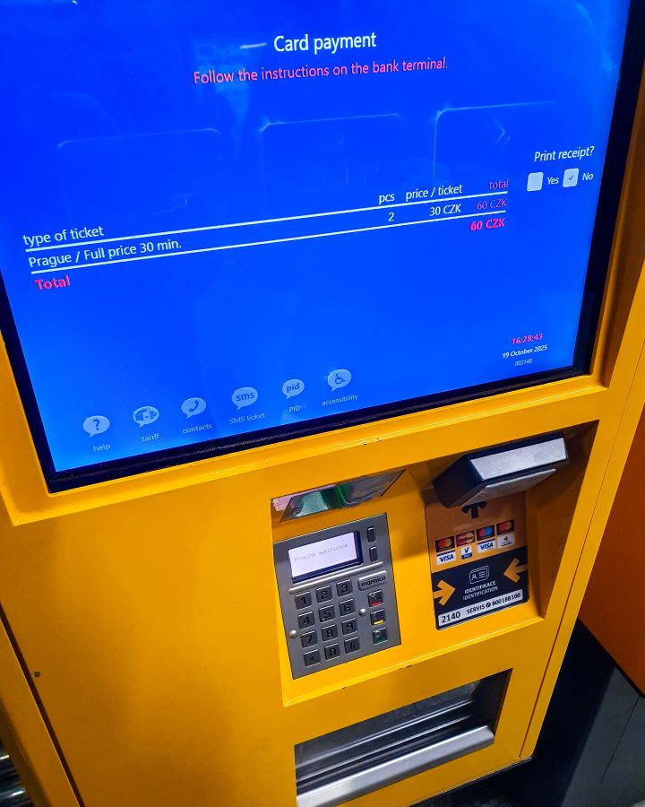 Prague Czechia A Complete Guide to Prague Public Transport A yellow ticket machine at a metro station in Prague, Czechia. The machine has a blue screen with spots to tap your payment card and get your ticket from underneath. A Complete Guide to Prague Public Transport