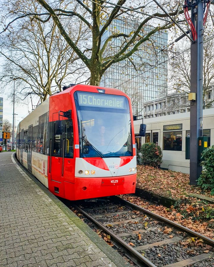 Cologne Bonn Germany How To Make The Most of a Day in Bonn from Cologne A red and white tram going through a station in Cologne, Germany that says 15 Chorweiler on it. Above it are trees with bushes around and the paved platform. How To Make The Most of a Day in Bonn from Cologne