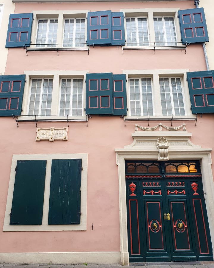 Beethoven Bonn Germany How To Make The Most of a Day in Bonn from Cologne A light pink house with white windows, blue window shutters and a blue and pink door. It was Beethoven's house in Bonn, Germany. How To Make The Most of a Day in Bonn from Cologne