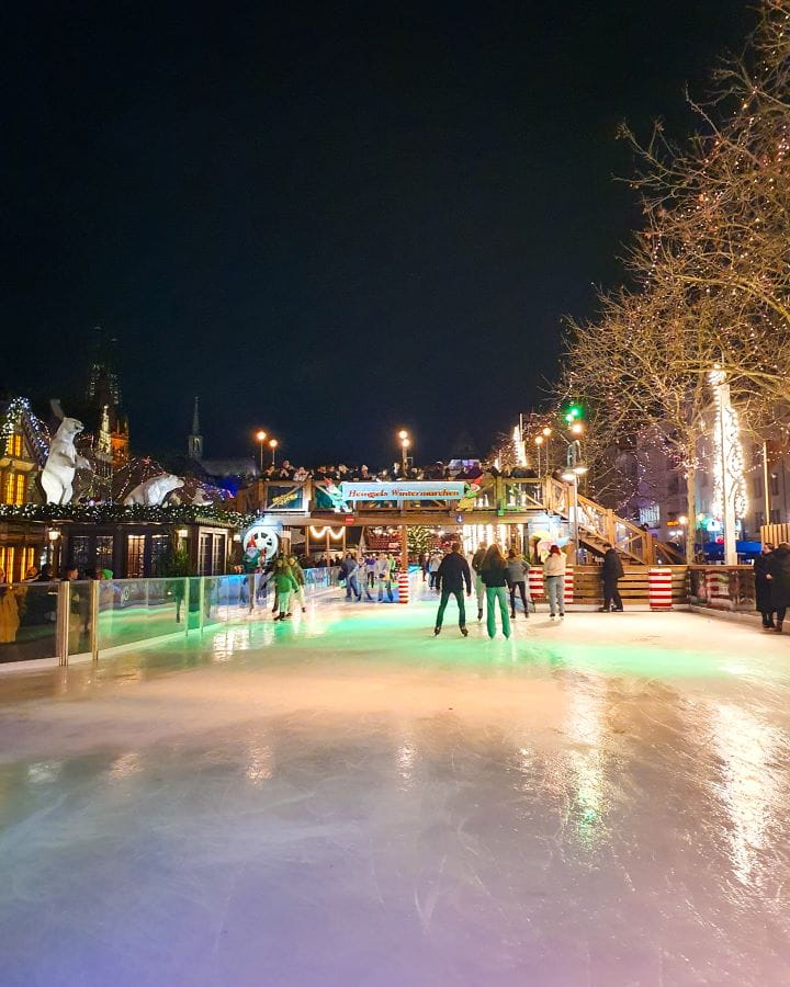 Heumarkt Complete Guide to the Magical Cologne Christmas Markets An ice skating rink with people on it at night at Heumarkt in Cologne, Germany. There's a wooden bridge going over the rink with a building on one side where you can get drinks. Complete Guide to the Magical Cologne Christmas Markets