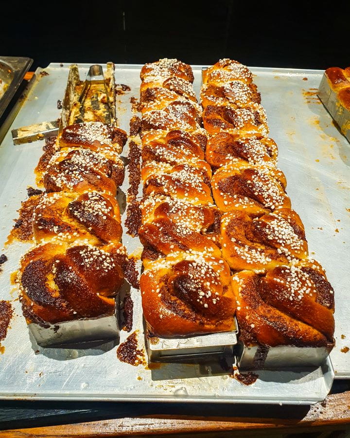 Pulla Bakery Cinnamon Buns Tallinn Estonia How To Do Helsinki and Tallinn In a Weekend A metal tray with 18 brown glazed cinnamon buns with white sugar on top. This was at Pulla Bakery in Tallinn, Estonia. How To Do Helsinki and Tallinn In a Weekend