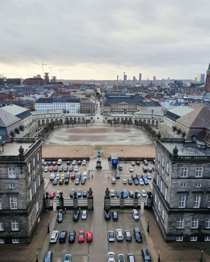 Christiansborg Palace Denmark How to Enjoy Your Time in Copenhagen For Free The view from the Christiansborg Palace tower in Copenhagen, Denmark. On the ground are lots of cars, a big empty square, and lots of white buildings with dark roofs going into the distance. How to Enjoy Your Time in Copenhagen For Free
