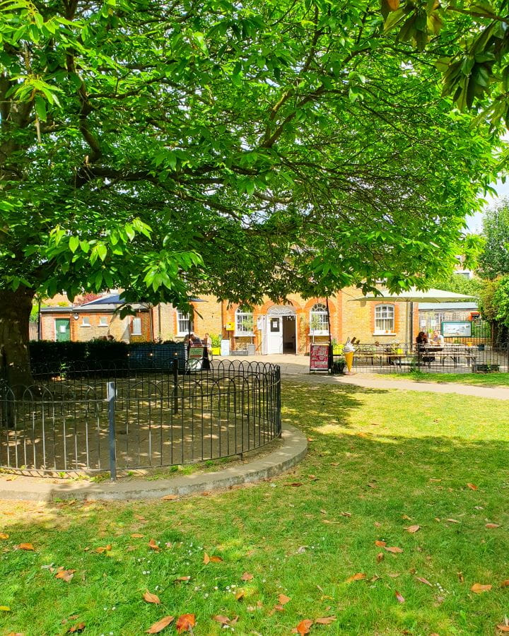 United Kingdom The Paddenswick Tea Gardens Ravenscourt Park Nine Less Touristy But Wonderful Parks to Visit in London A little café in Ravenscourt Park, London. There's a metal wire fence on the left with the orange brick café behind it. There's chairs and tables out the front with people sitting at them and a path leading away from the café. Nine Less Touristy But Wonderful Parks to Visit in London